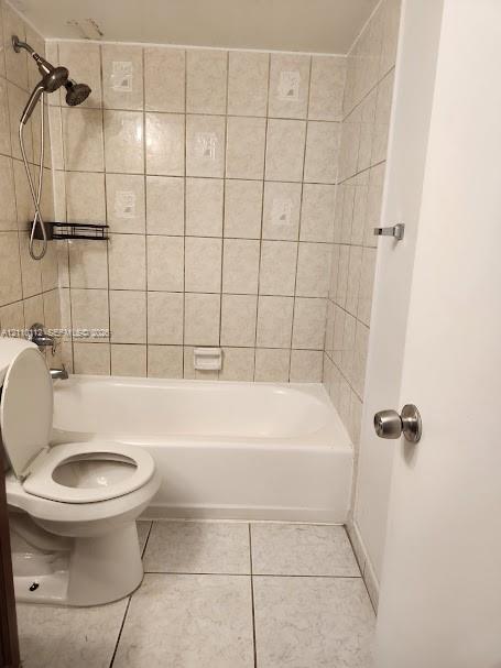 Bathroom featuring a porcelain tub, wall-mounted shower head, ceramic wall tiling, and light-toned tile flooring