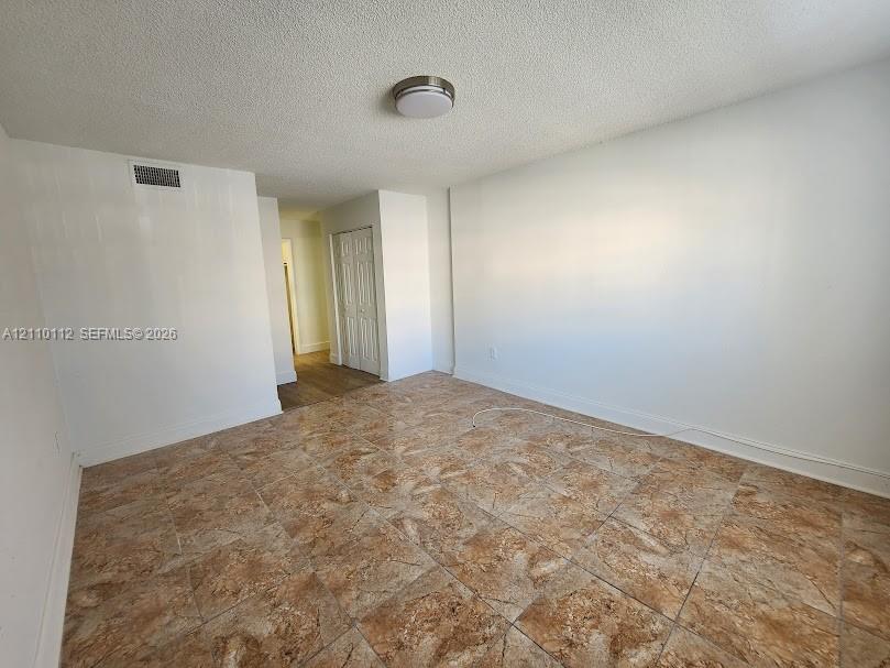Interior room featuring tile flooring, smooth white walls, and a recessed ceiling-mounted light fixture, complemented by double-door closet cabinetry
