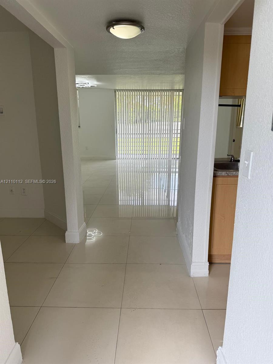 Large-format tile flooring, flush-mount ceiling lighting, and vertical sliding glass door panels