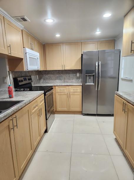 Kitchen featuring light-finish cabinetry, stone-texture countertops, tile flooring, recessed ceiling lighting, and stainless steel appliances