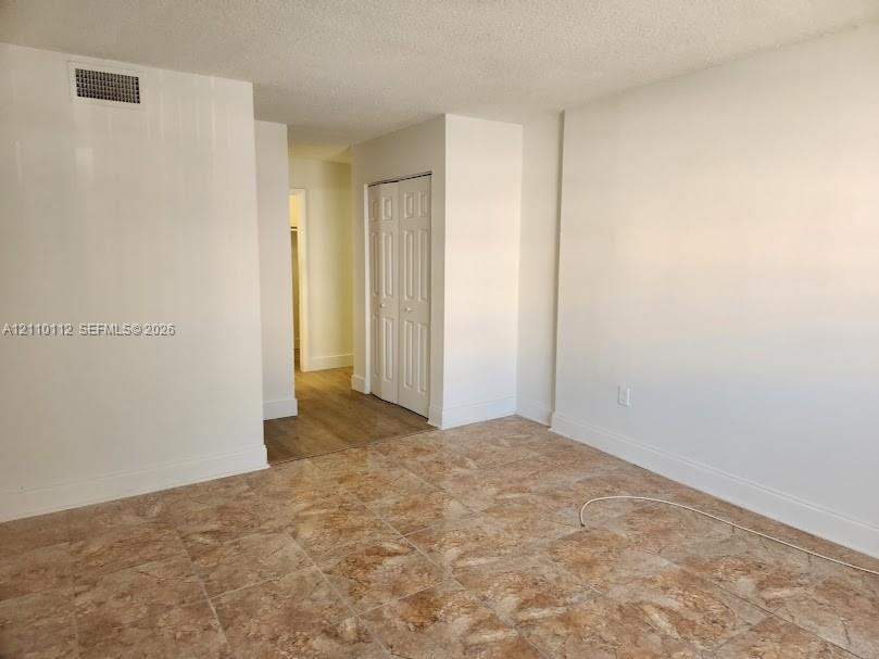 Interior space featuring neutral wall tones, large-format tile flooring, wood-finish flooring, and a built-in bifold closet