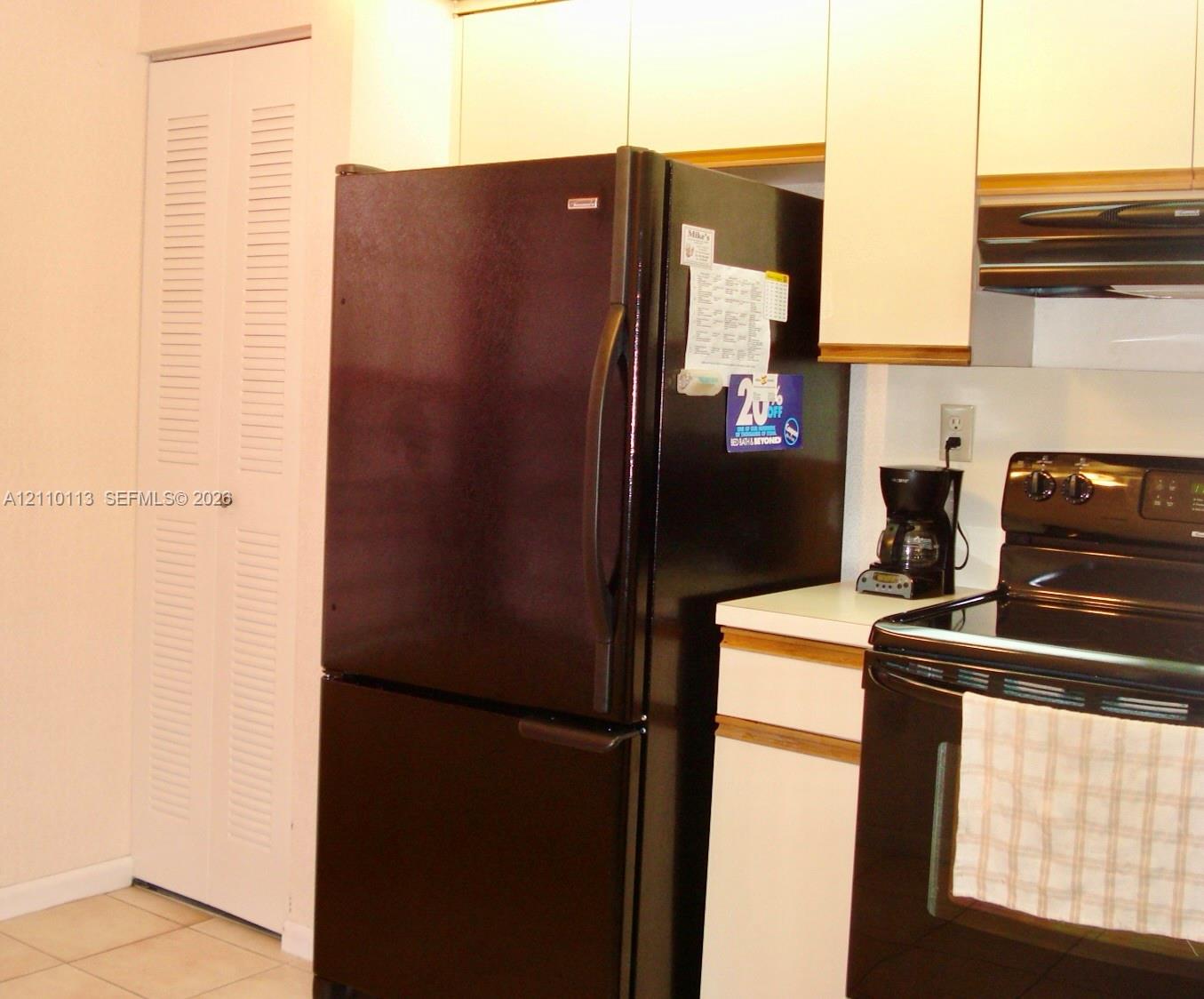 Kitchen featuring flat-panel cabinetry, solid-surface countertops, black-finish appliances, and a closet with bifold louvered doors