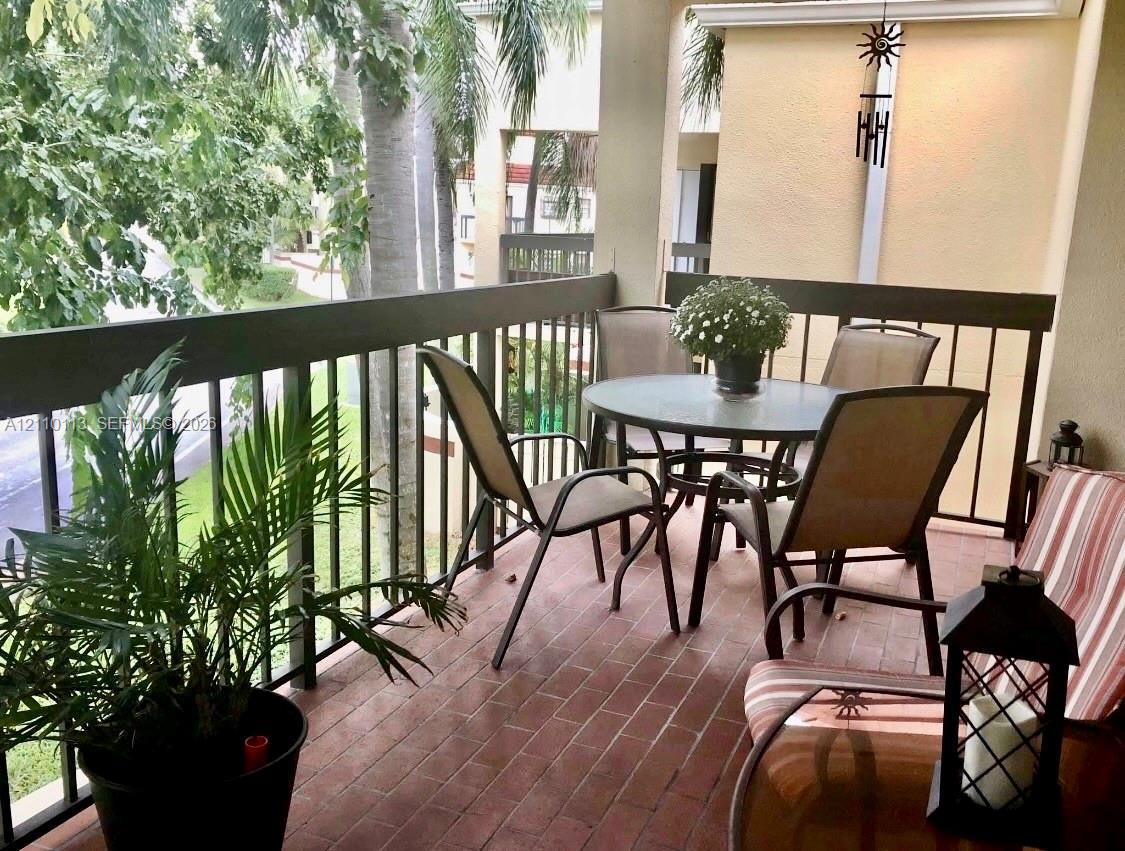 Covered balcony featuring red brick-style flooring and a dark metal railing
