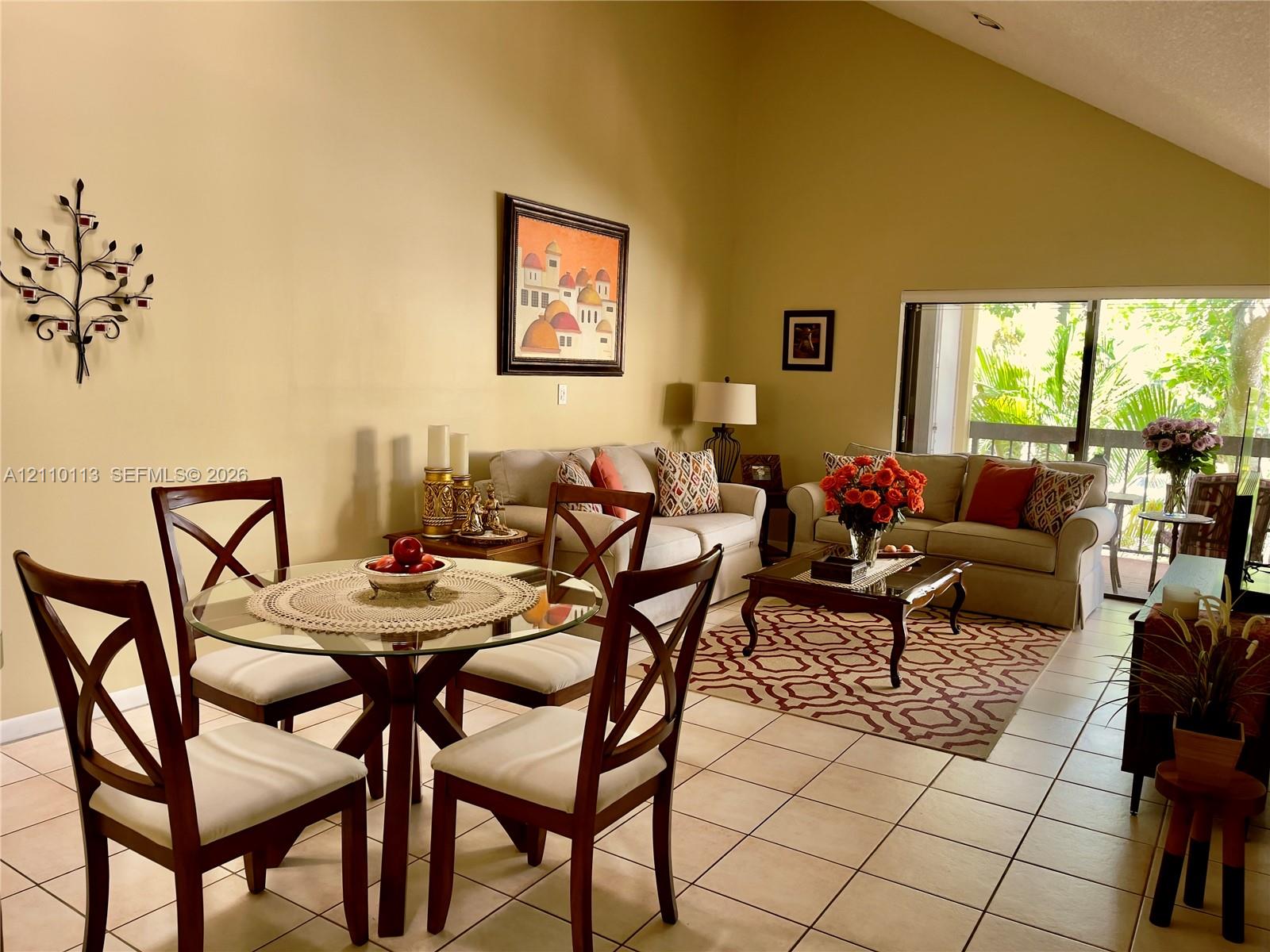 Vaulted ceilings, neutral wall finishes, tile flooring, and sliding glass doors with access to the outdoors