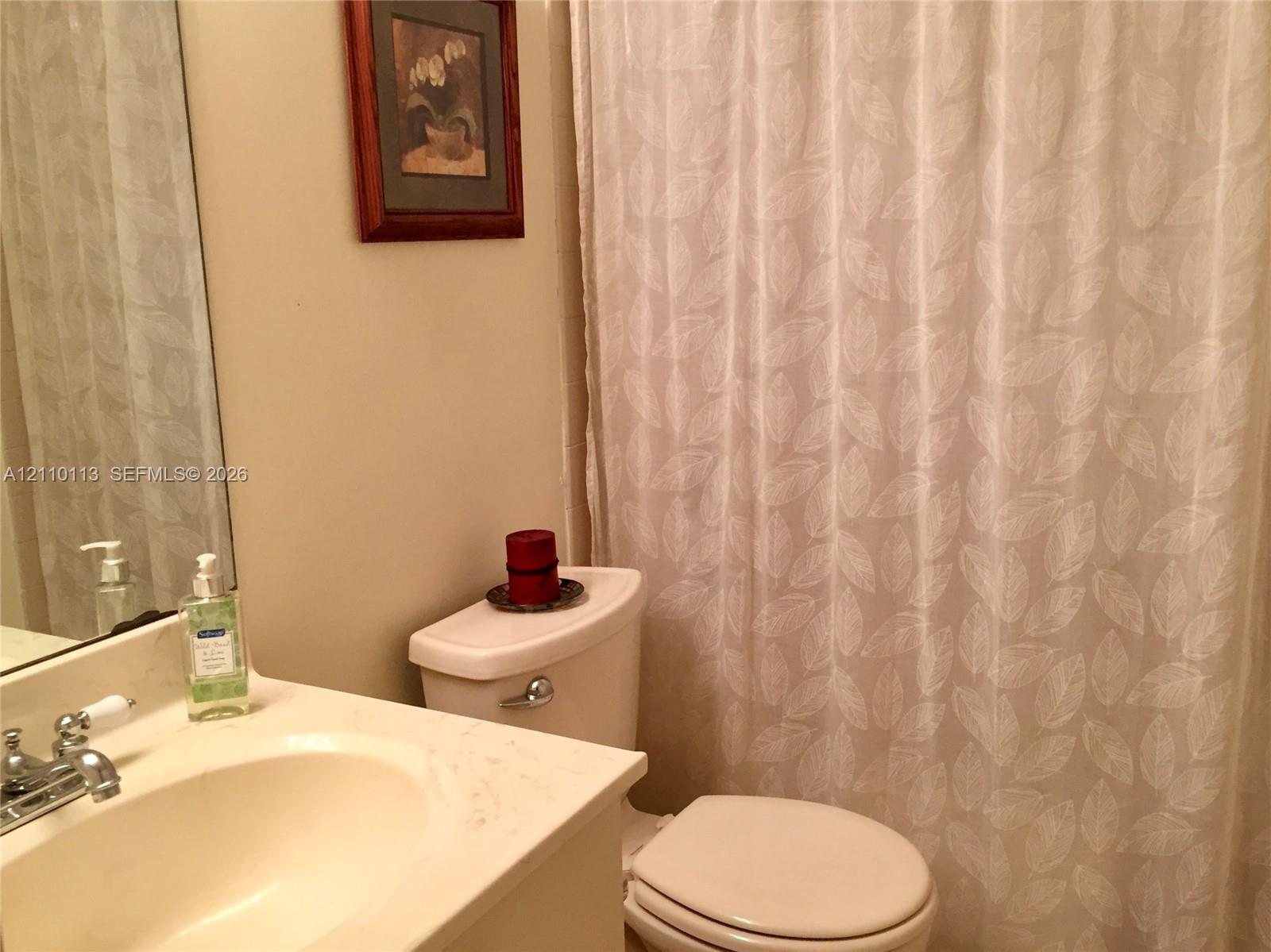 Bathroom featuring a vanity with a light-toned countertop, integrated oval basin, and dual-handle metal faucet, paired with a standard-height toilet