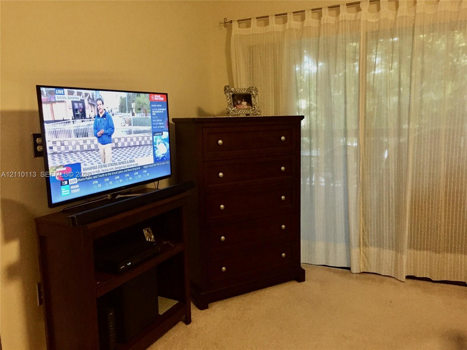 Large sliding glass door with a decorative metal curtain rod and neutral wall-to-wall carpeting