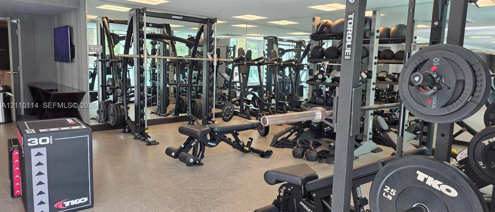 Fitness center featuring floor-to-ceiling mirrors, recessed lighting, and rubberized flooring