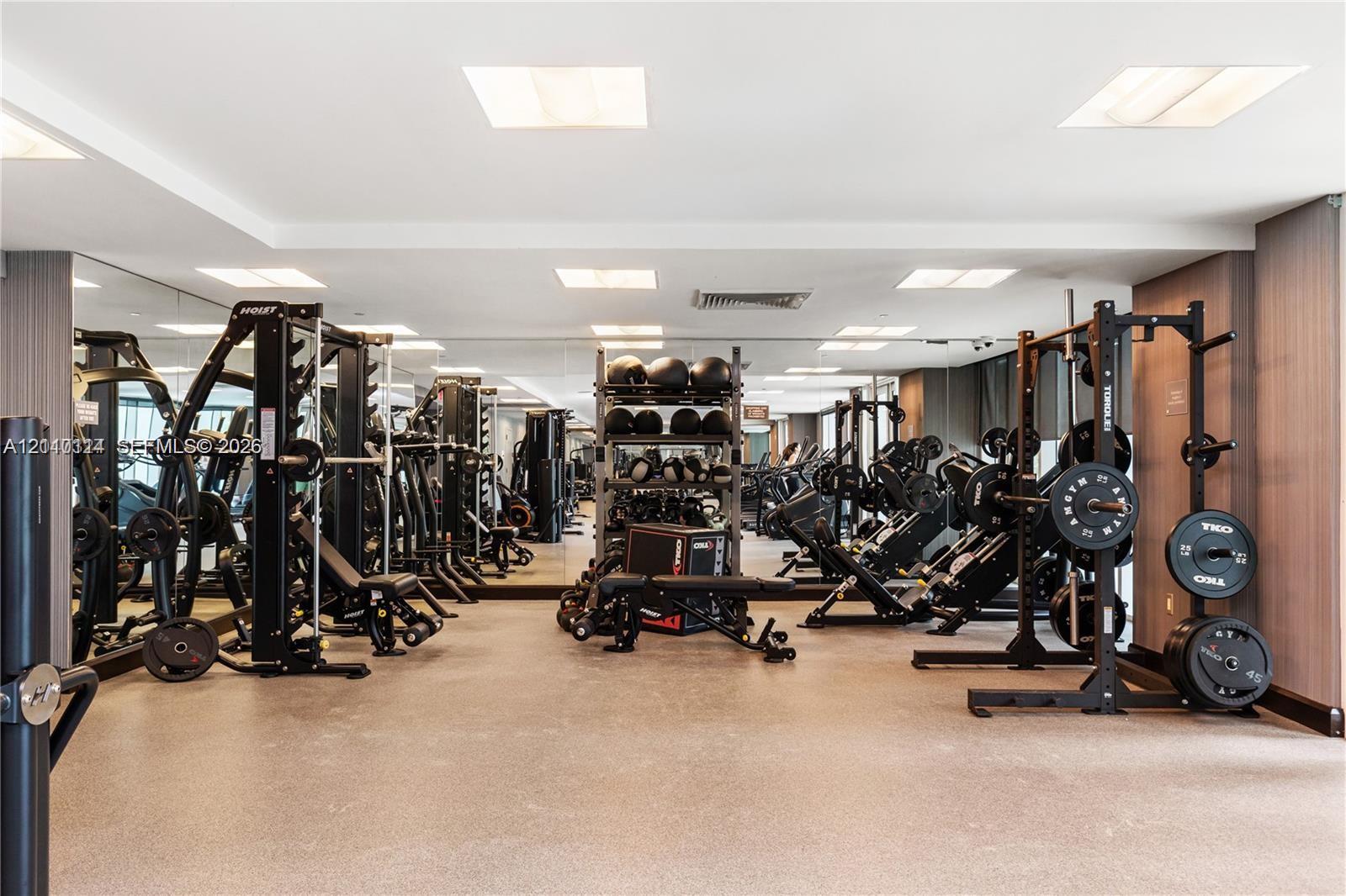 Fitness center featuring wall-to-wall mirrors, recessed lighting, and resilient composite flooring