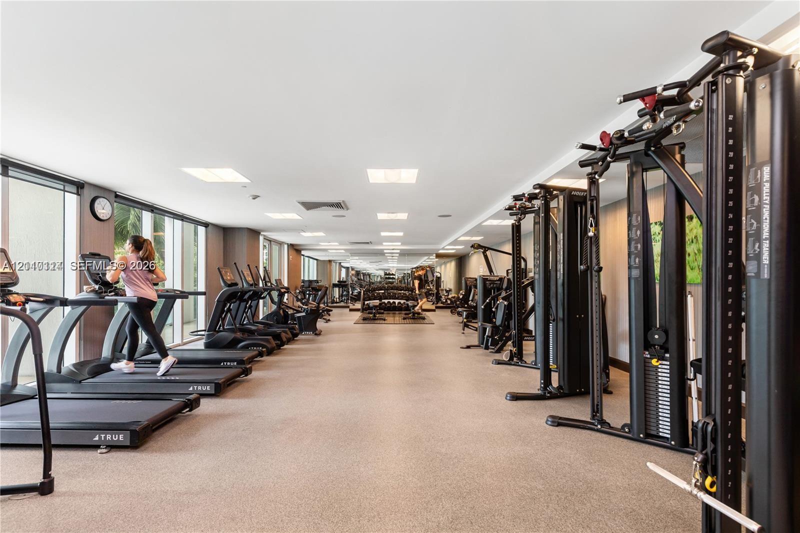 Fitness center featuring expansive floor-to-ceiling windows, recessed lighting, rubberized flooring, and an array of professional-grade strength and cardiovascular equipment