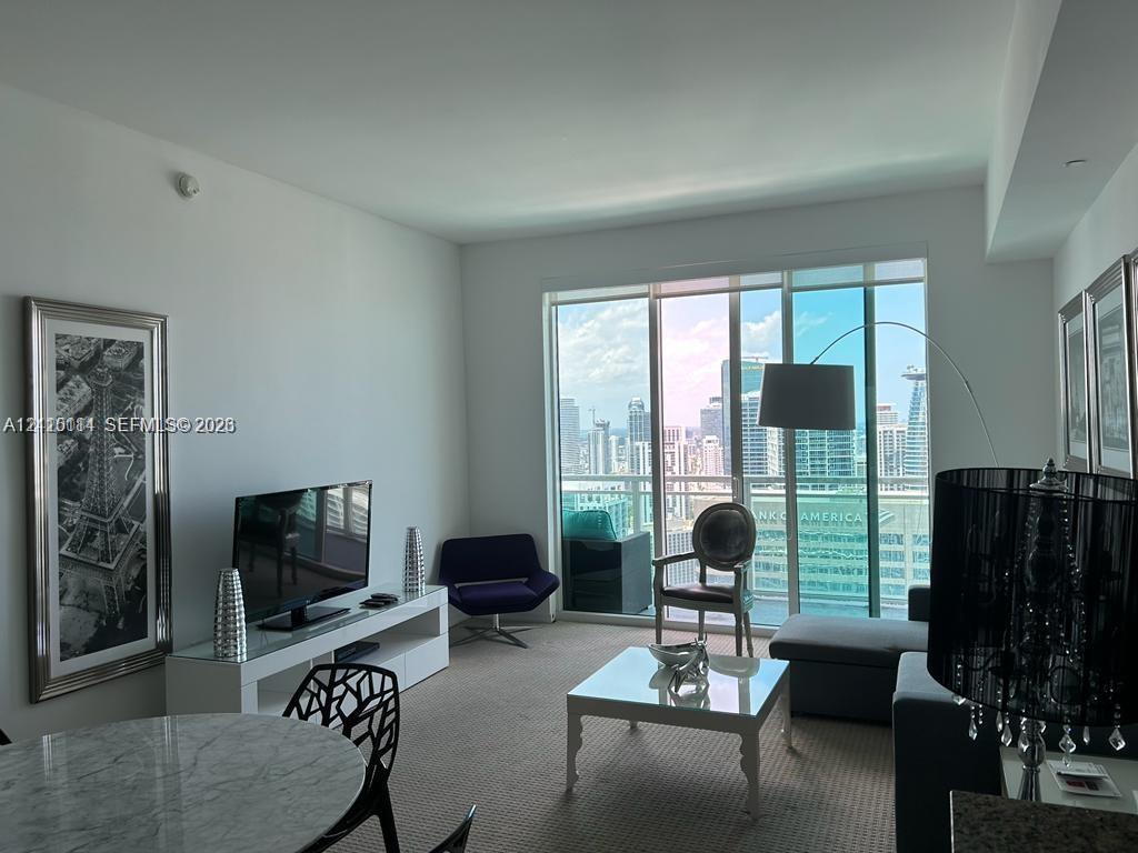 Floor-to-ceiling glass windows, private balcony, and neutral carpeting