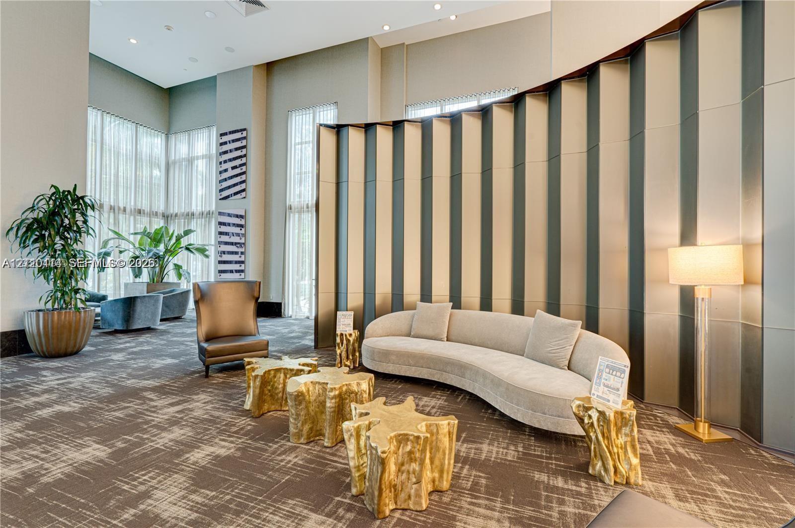 Double-height ceilings featuring floor-to-ceiling windows, recessed lighting, and a prominent curved feature wall with vertical metallic paneling