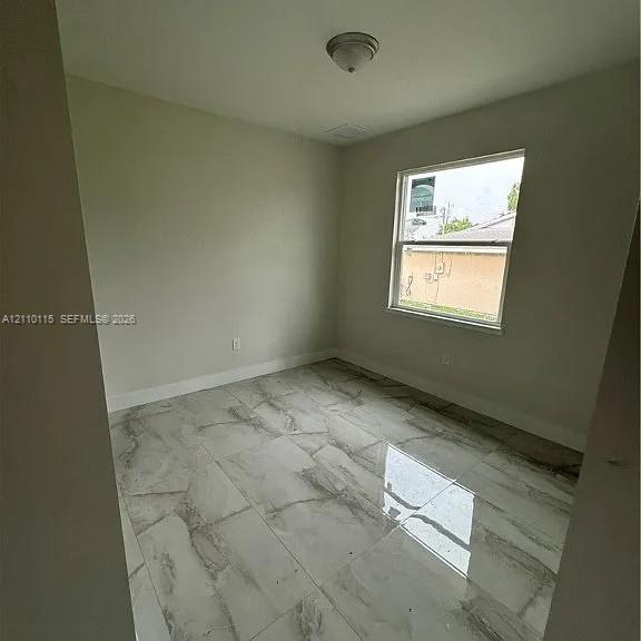 Neutral-toned walls paired with large-format, glossy stone-finish floor tiling and a single-pane window
