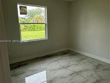 Interior room featuring neutral wall paint and polished stone-finish floor tile