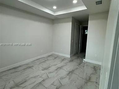 Tray ceiling with recessed lighting and large-format polished tile flooring