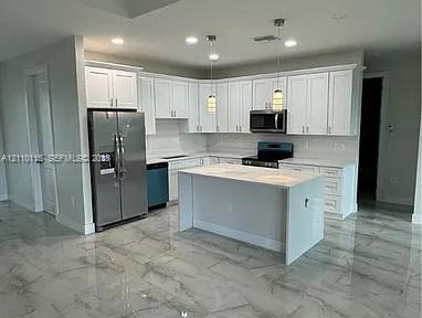 Kitchen featuring white cabinetry, center island with stone-finish countertop, stainless steel refrigerator, built-in microwave, and large-format tile flooring