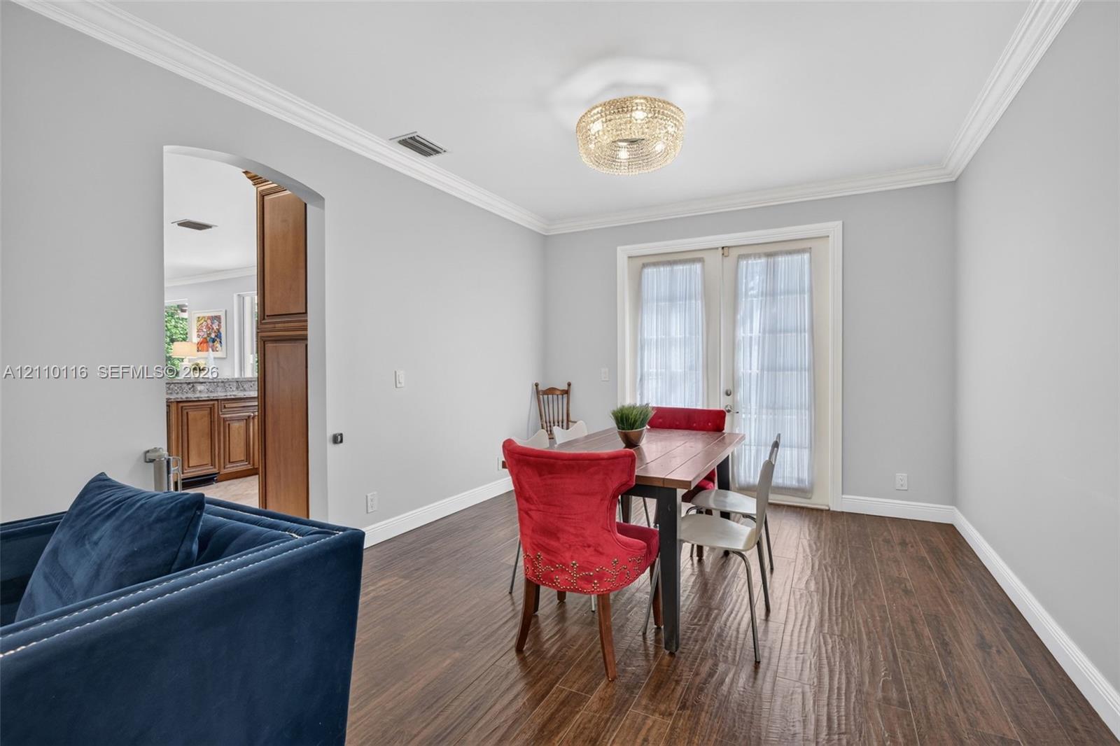 Wood-finish flooring, crown molding, a decorative circular flush-mount light fixture, and French doors Wood-finish flooring, crown molding, a decorative circular flush-mount light fixture, and French doors