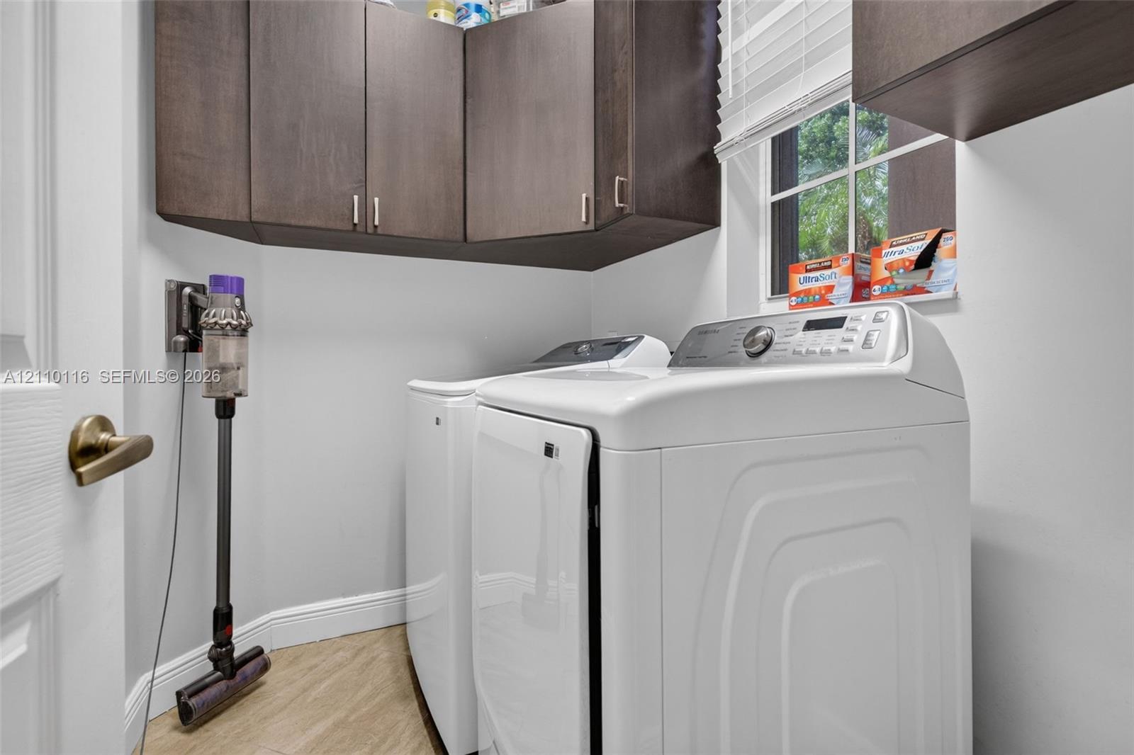 Laundry space featuring dark-finish built-in cabinetry, light wood-finish flooring, and a multi-pane window