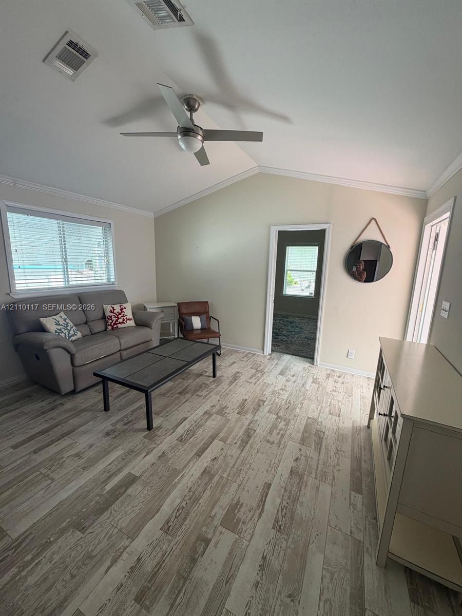 Vaulted ceiling featuring a ceiling fan and wood-finish flooring