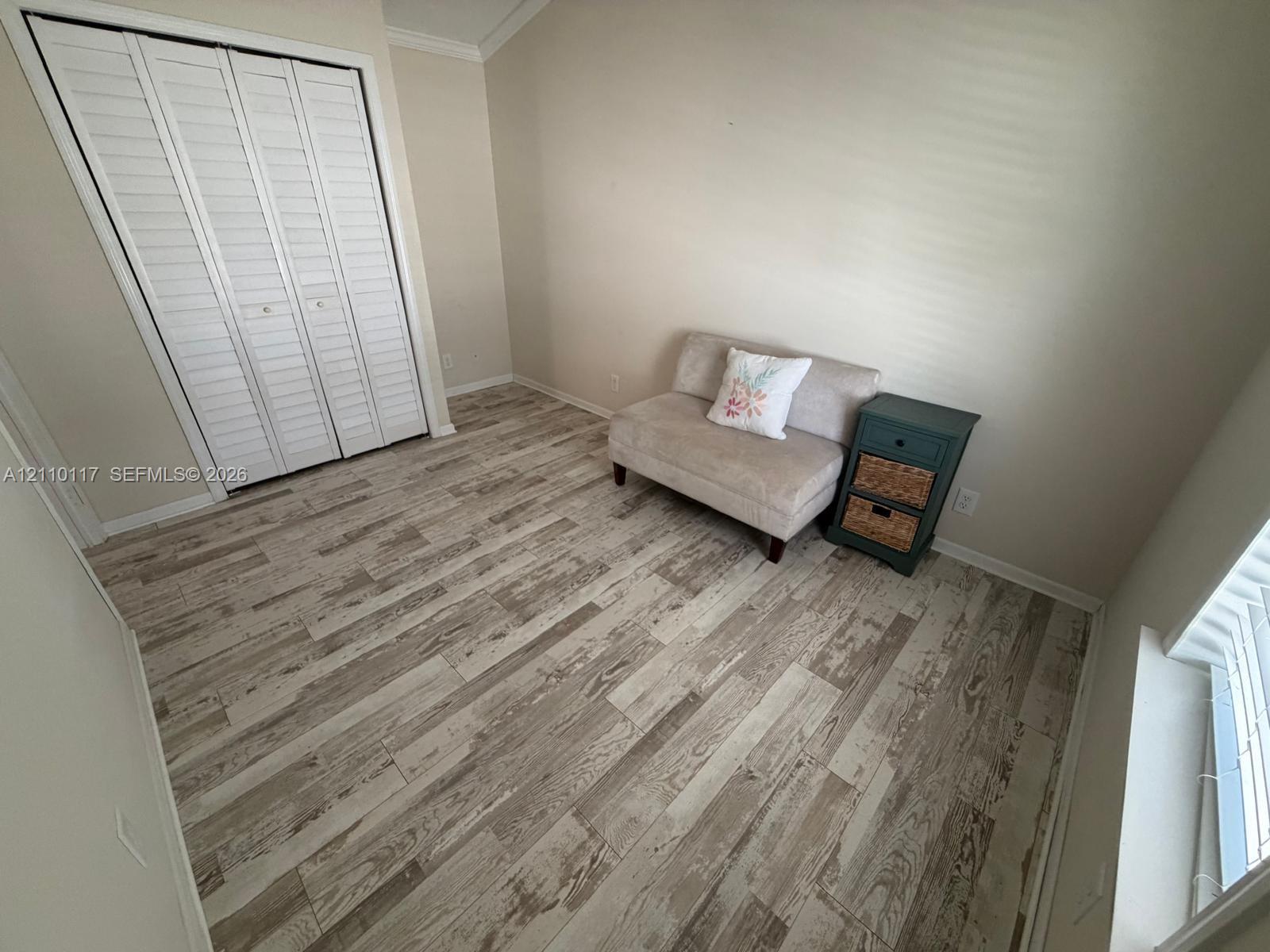 Room featuring wood-finish flooring, vaulted ceilings, and a double-door closet with louvered panels