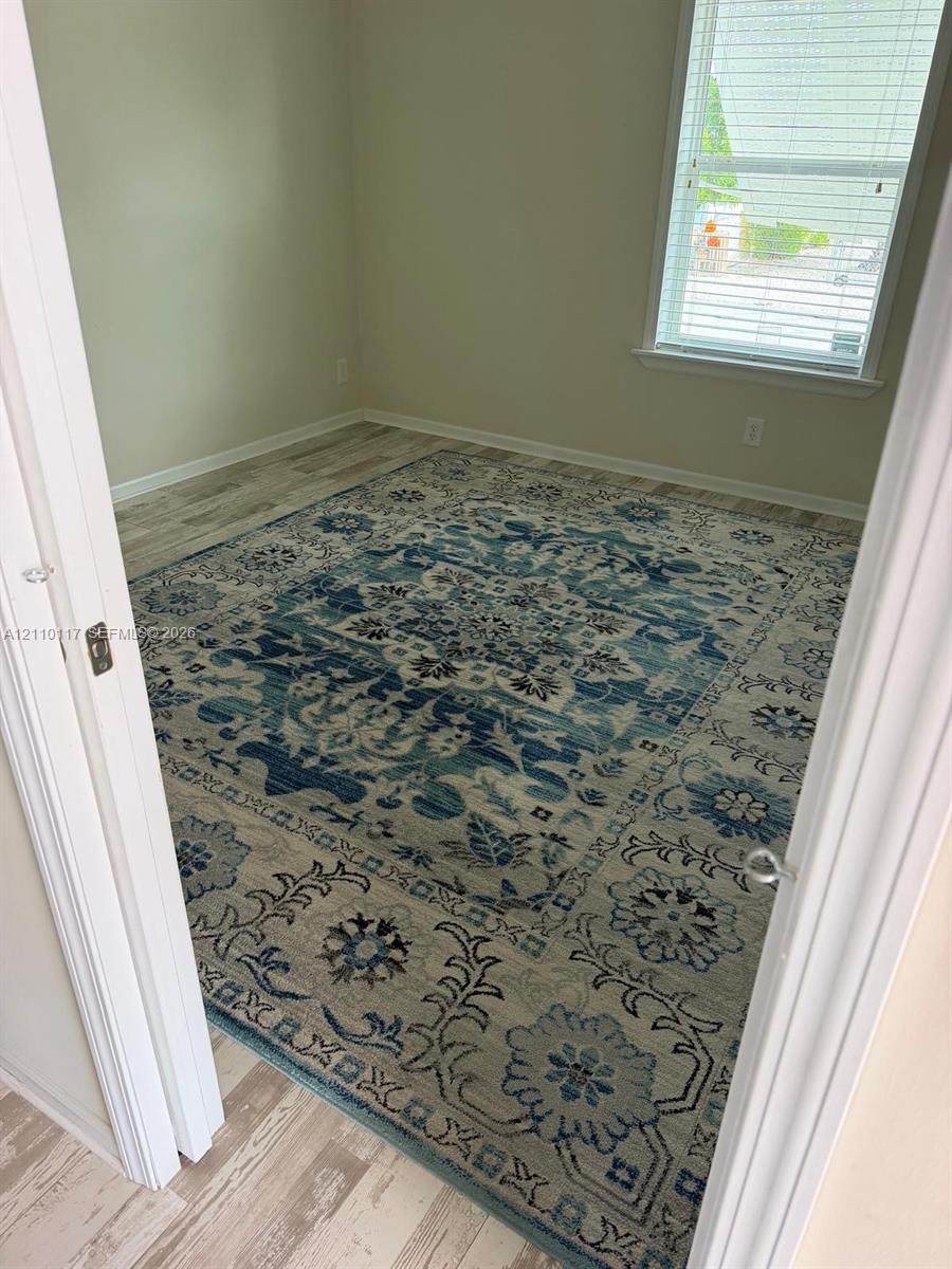 Room featuring wood-finish flooring and a window with horizontal blinds
