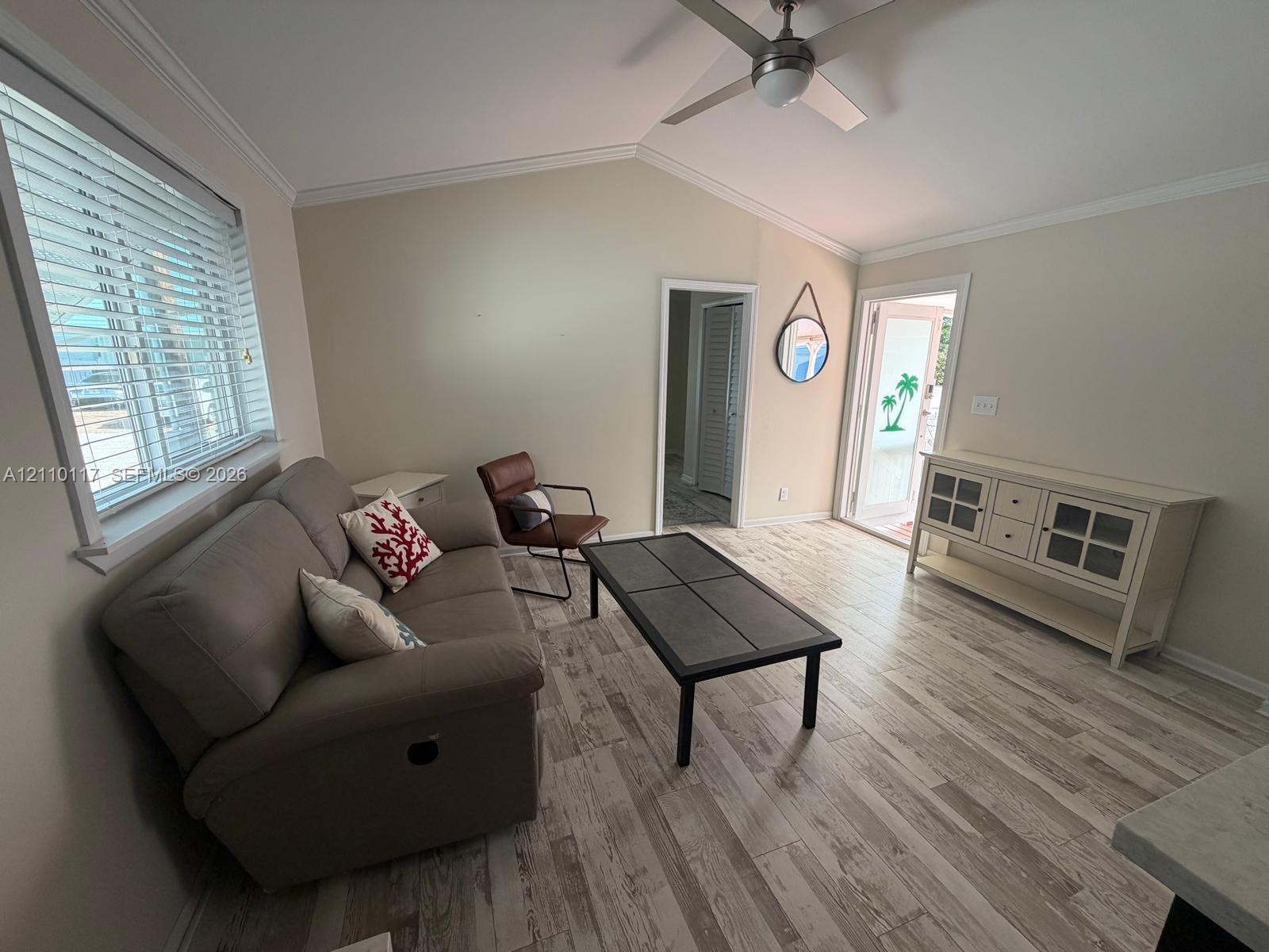 Vaulted ceiling featuring a central brushed-nickel ceiling fan, wood-finish tile flooring, and horizontal window blinds
