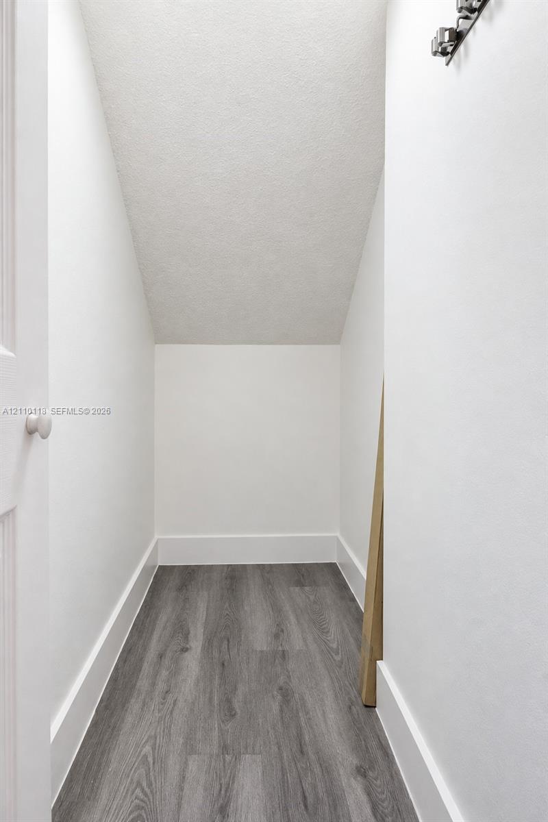 Storage area featuring wood-finish flooring, white walls, and a multi-bulb ceiling fixture