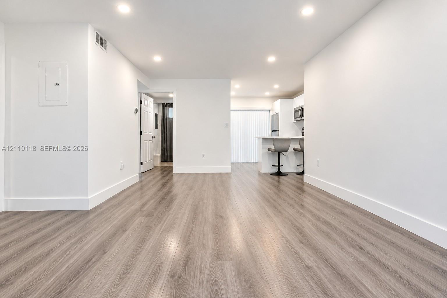 Open interior featuring wood-finish flooring, recessed lighting, and a kitchen peninsula with integrated appliances