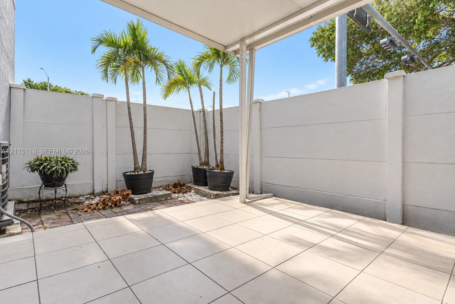 Covered patio featuring large-format tile flooring and a privacy wall enclosure
