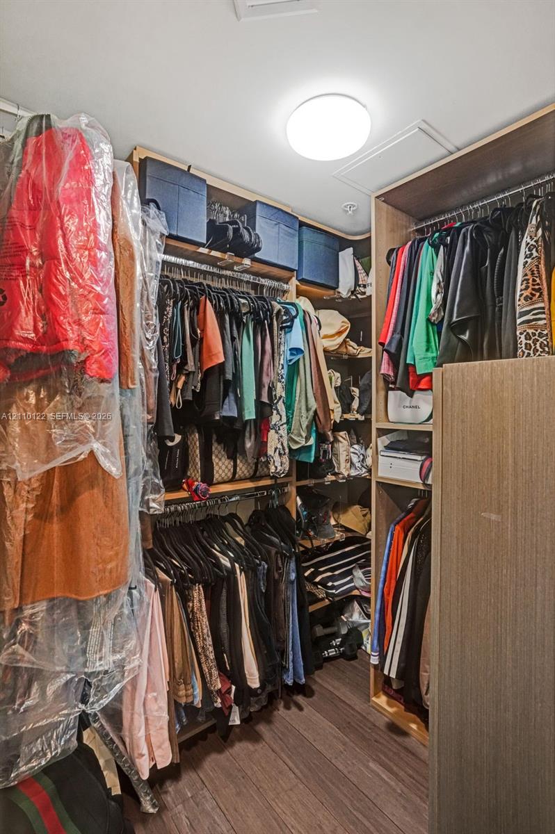 Custom walk-in closet featuring floor-to-ceiling wooden cabinetry, tiered hanging rods, integrated shelving units, and flush-mount overhead lighting