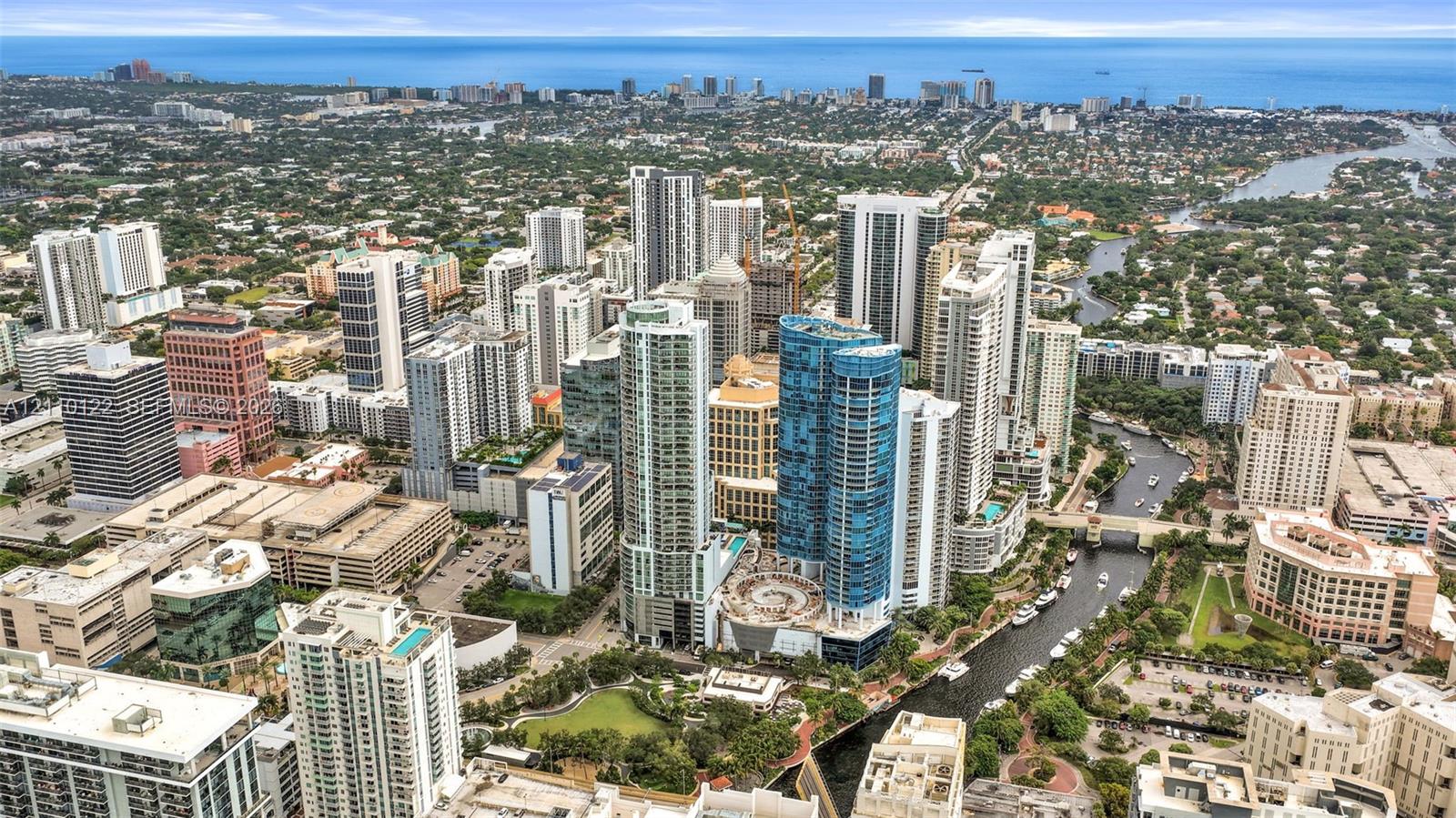 Aerial perspective featuring dense urban high-rise development, a central waterway, and immediate proximity to the coastline