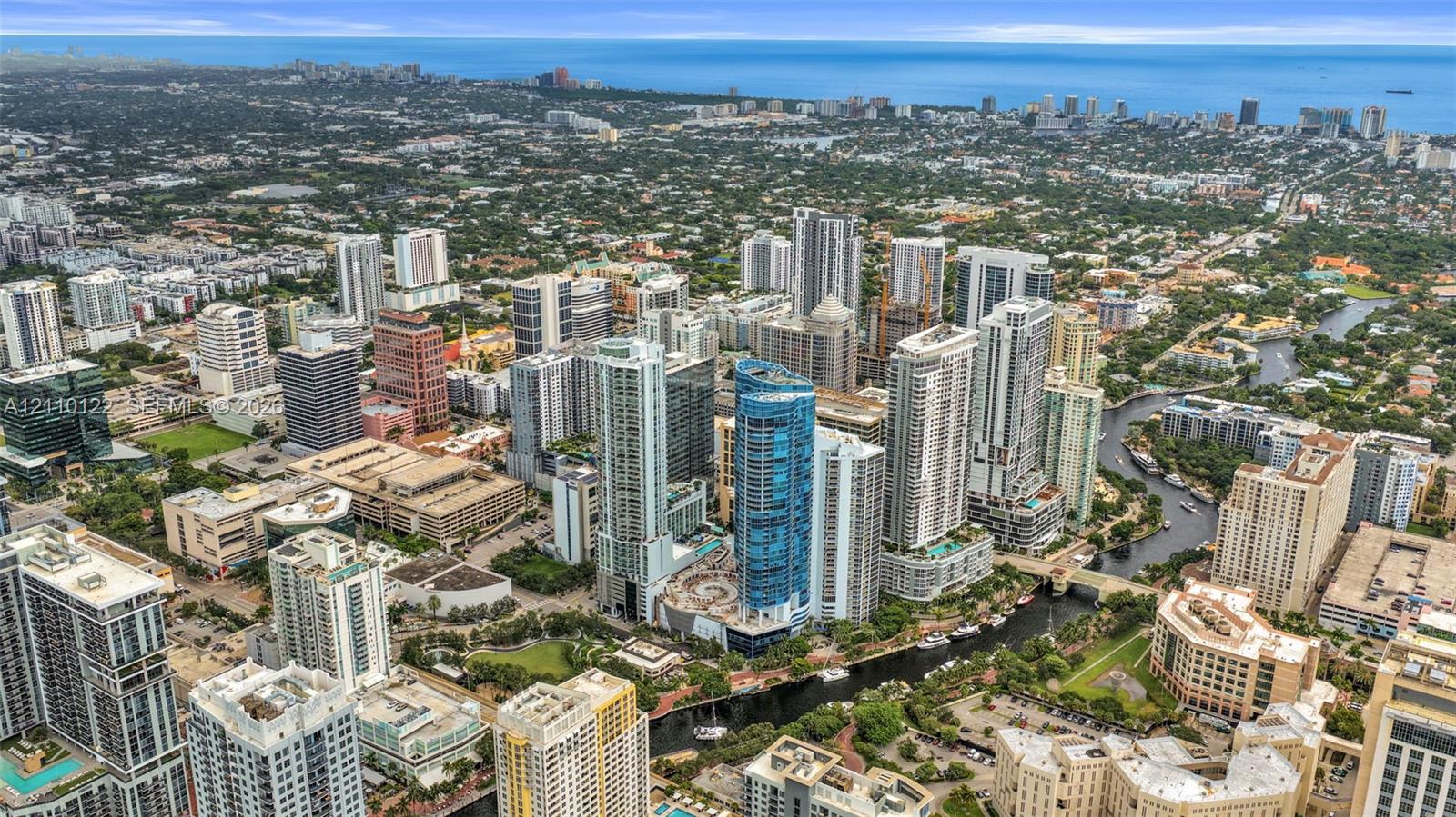 Aerial perspective of an urban cityscape featuring high-rise architecture, a navigable river system, coastal proximity, and established metropolitan infrastructure