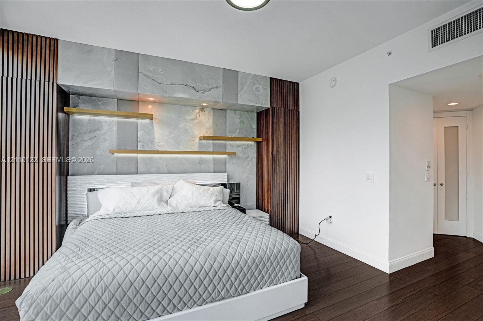 Floor-to-ceiling wood-slat paneling, stone wall feature, integrated display shelving with recessed lighting, and wood-finish flooring