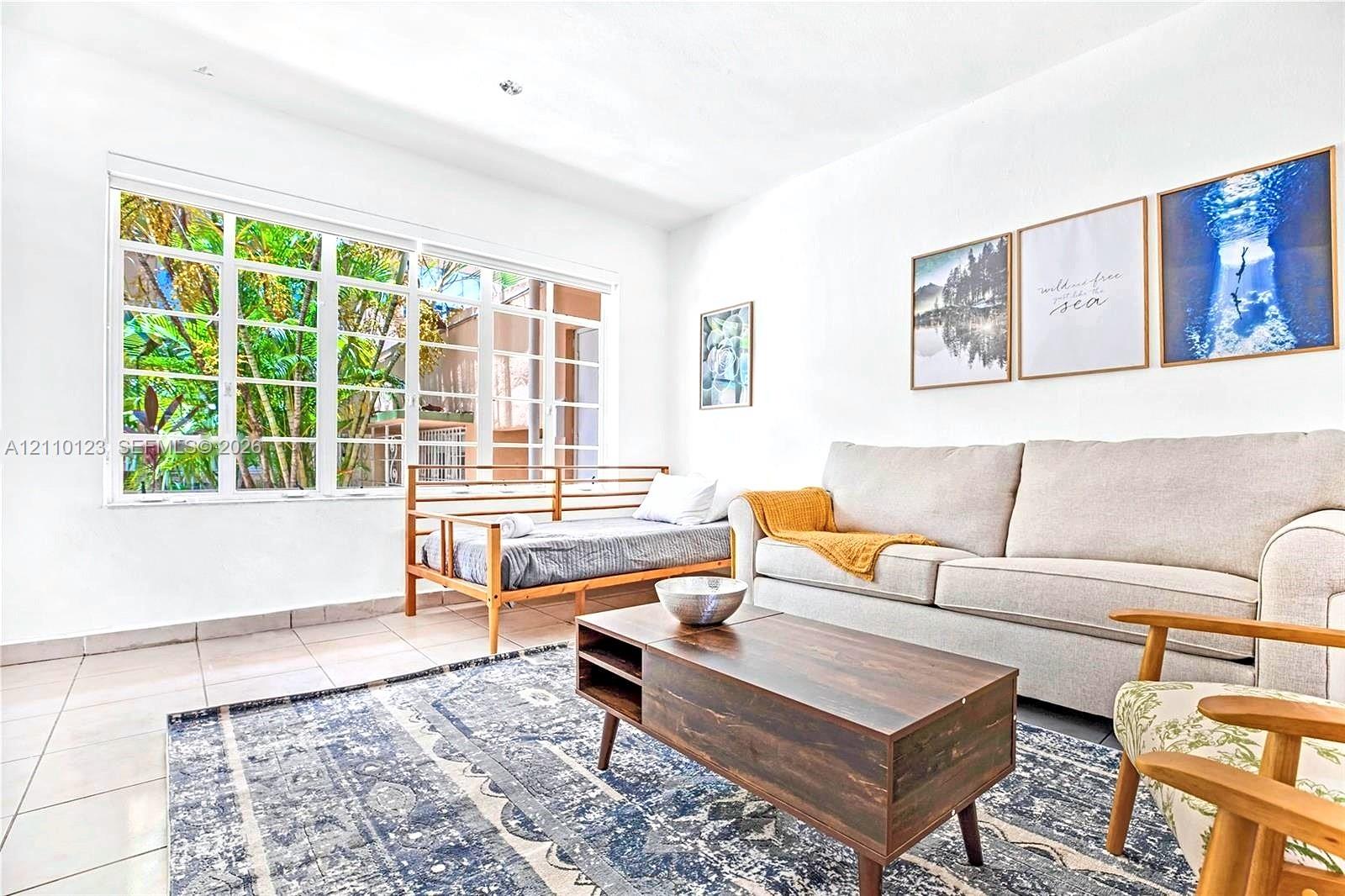 Large grid-pattern window providing abundant natural light, neutral ceramic tile flooring, and recessed ceiling lighting