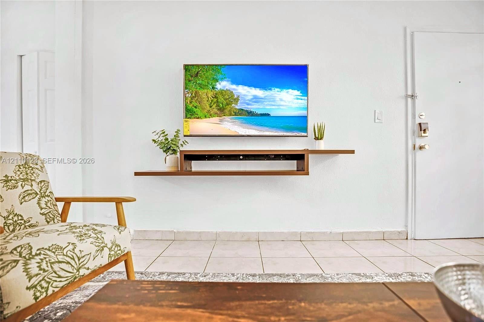 Wall-mounted wood-finish floating media console and light-colored ceramic tile flooring