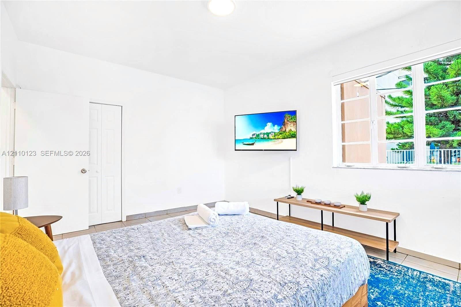 Room featuring neutral white walls, large multi-pane window, and smooth-surface tile flooring