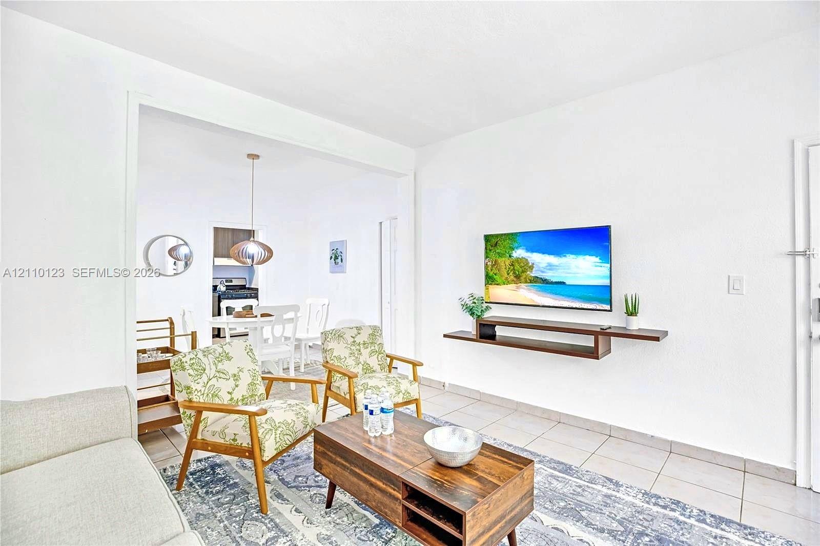 Neutral-toned ceramic tile flooring, clean-lined wall-mounted floating media shelf, and recessed ceiling lighting