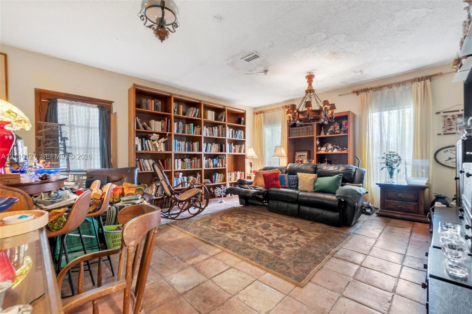 Built-in wall-to-wall wood shelving, ceramic tile flooring, and decorative metal chandelier