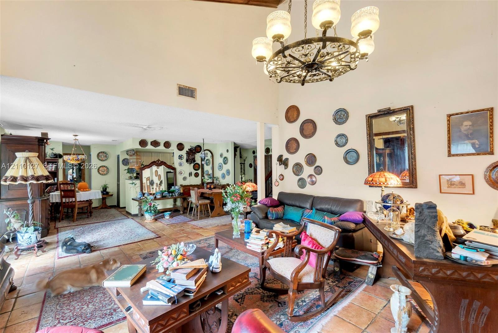 Vaulted ceilings with exposed wood beams, tile flooring, and a decorative wrought-iron chandelier