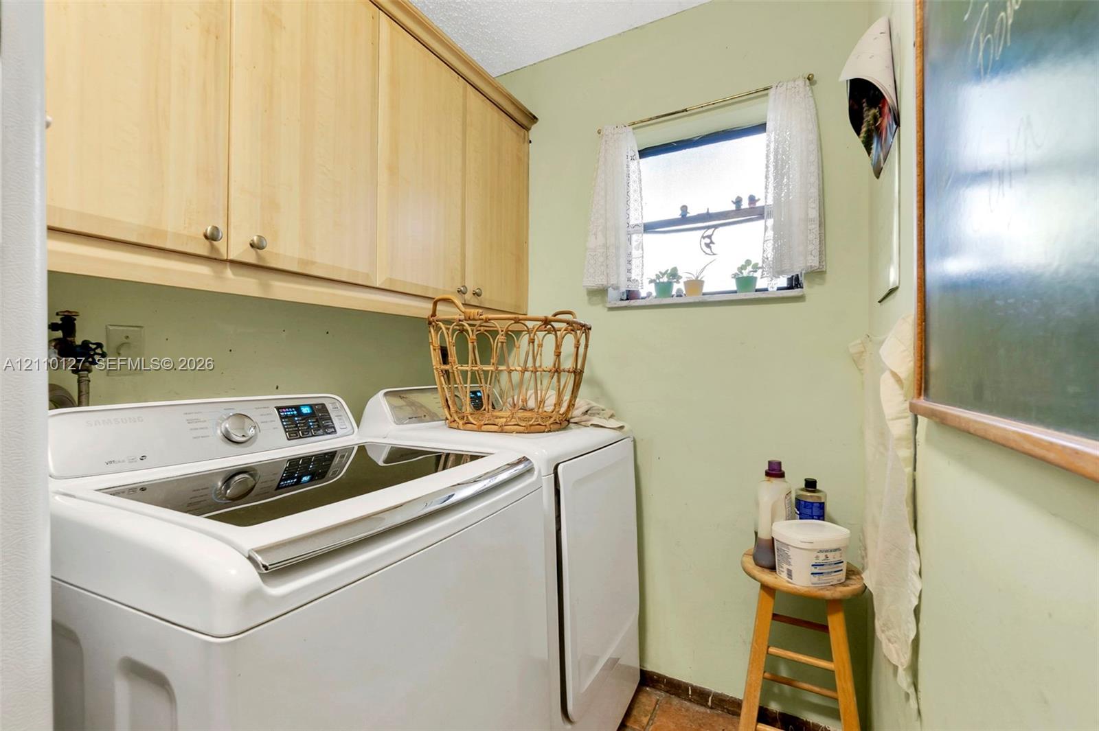 Laundry space featuring upper wood-finish cabinetry, a single-hung window, and dedicated plumbing connections
