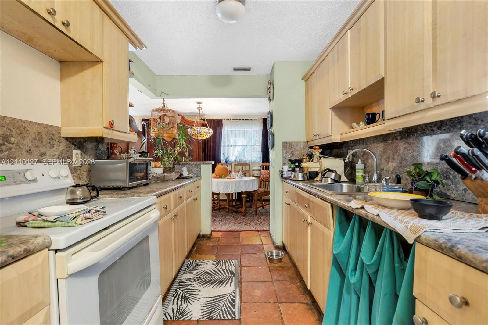 Kitchen featuring light-finish cabinetry, stone-patterned laminate countertops, tile flooring, and a stainless steel undermount sink