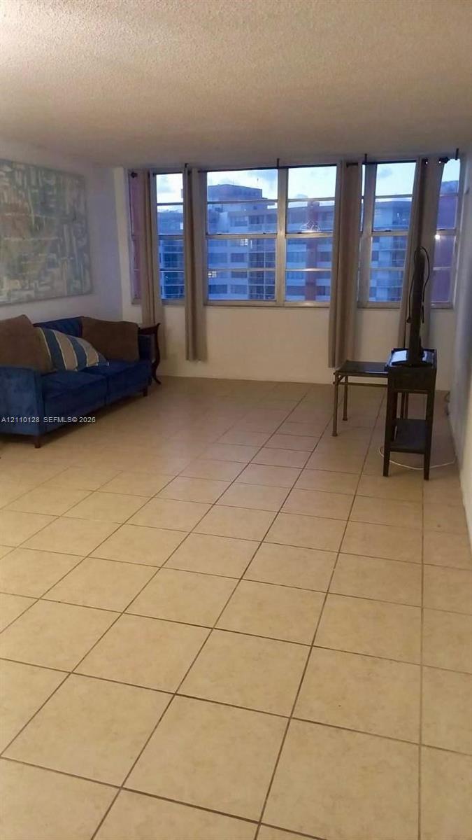 Expansive living space featuring neutral square floor tiles and a wall of floor-to-ceiling windows