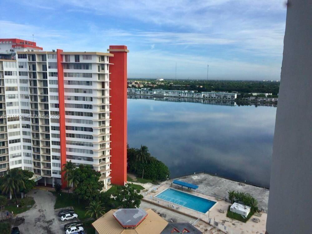 High-rise building exterior featuring a rectangular outdoor swimming pool, paved pool deck, and direct waterfront placement