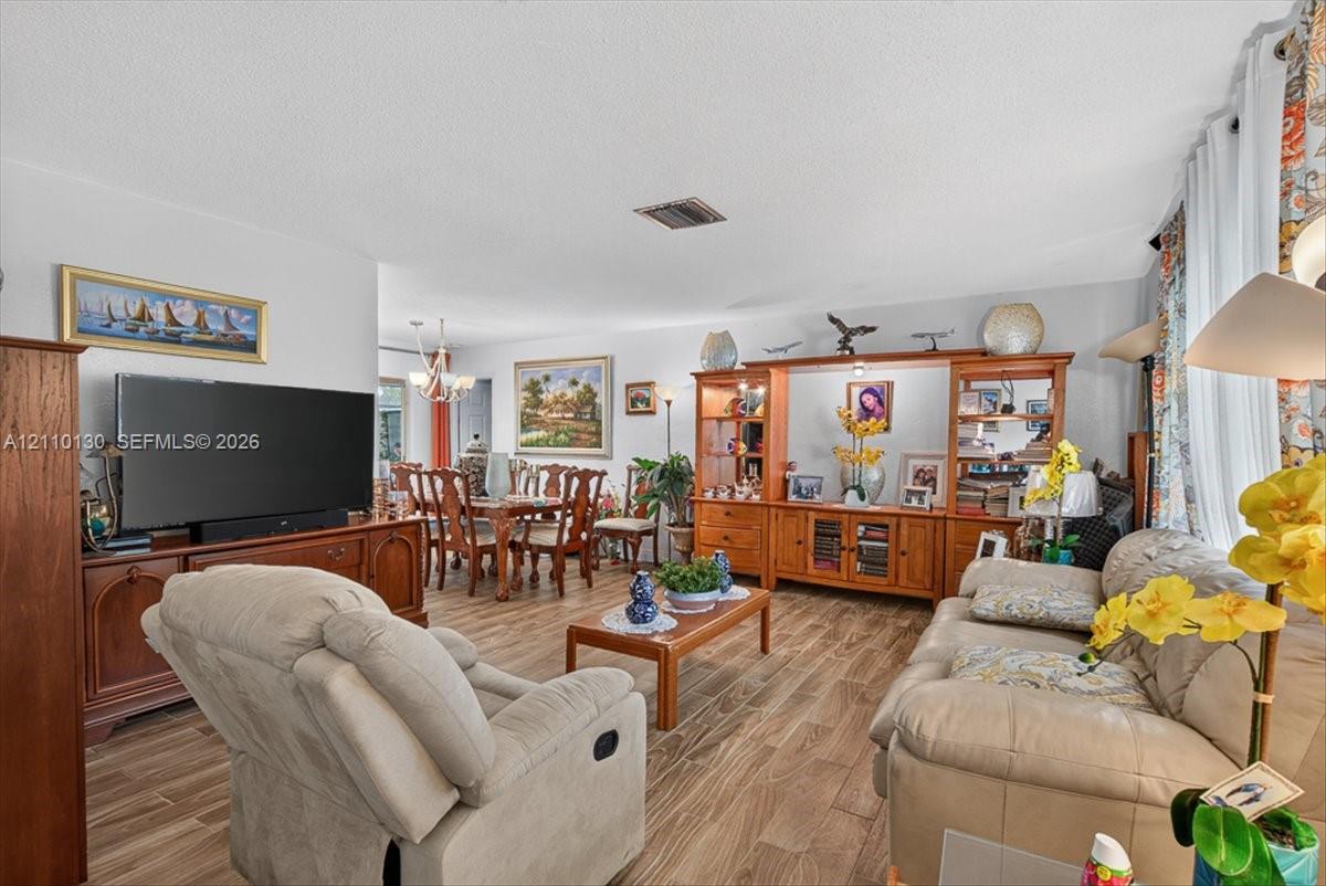 Open-concept floor plan featuring wood-finish flooring throughout, a large built-in wooden entertainment center, and a decorative chandelier
