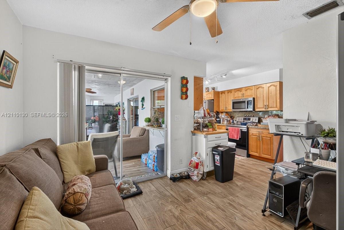 Kitchen featuring wood-finish cabinetry, stainless steel appliances, and wood-finish flooring with sliding glass patio doors