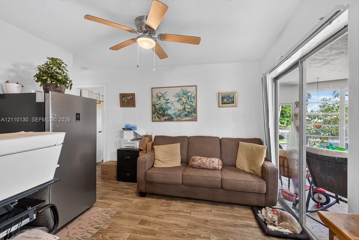 Wood-finish flooring, ceiling fan with integrated lighting, and sliding glass doors providing outdoor access