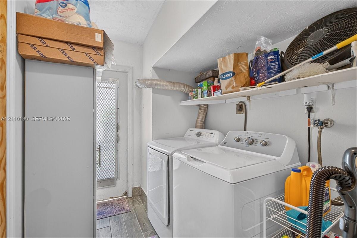 Laundry area featuring wood-finish tile flooring, white-finish wall-mounted shelving, and a metal-frame exterior door