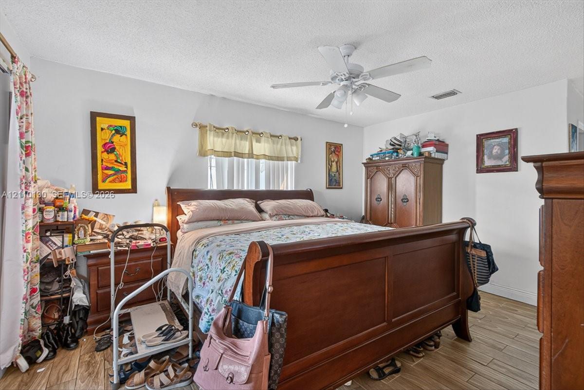 Wood-finish tile flooring, ceiling fan with integrated light fixture, and window with pleated valance