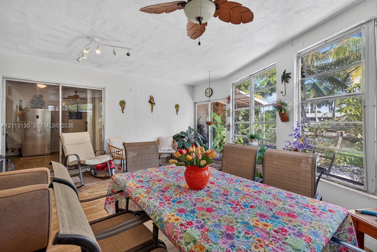 Enclosed patio featuring wood-finish flooring, ceiling fan with integrated lighting, multi-pane windows, and sliding glass entry doors