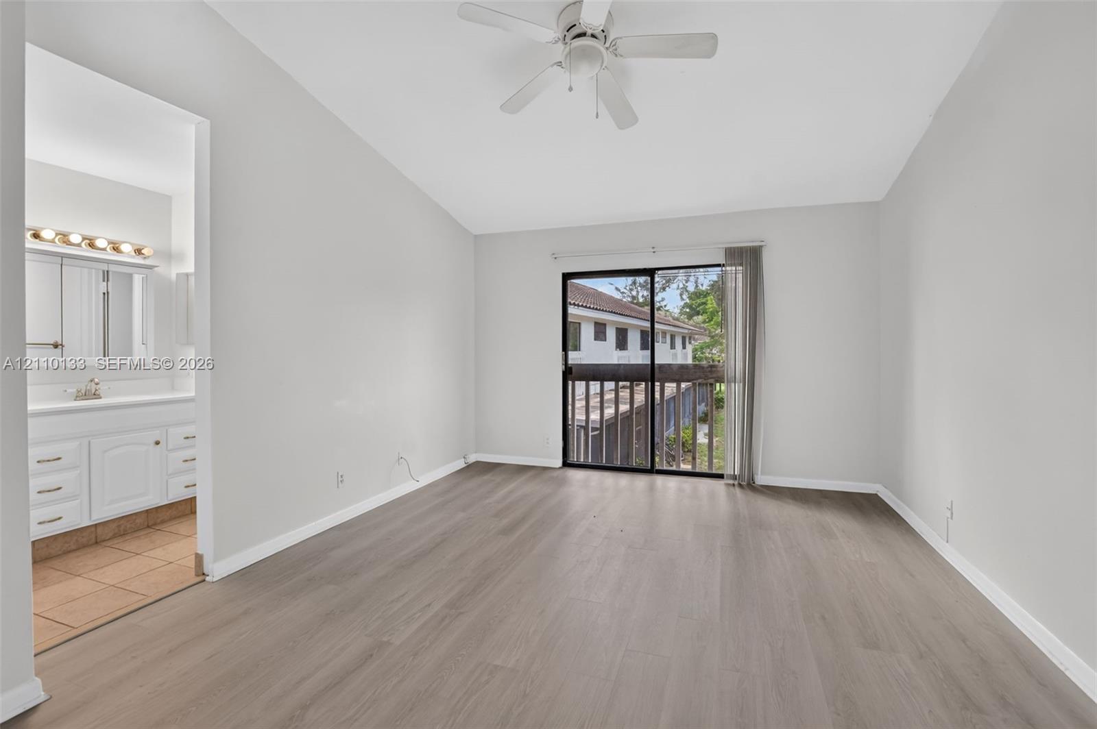 Room featuring wood-finish flooring, vaulted ceilings, and a ceiling fan