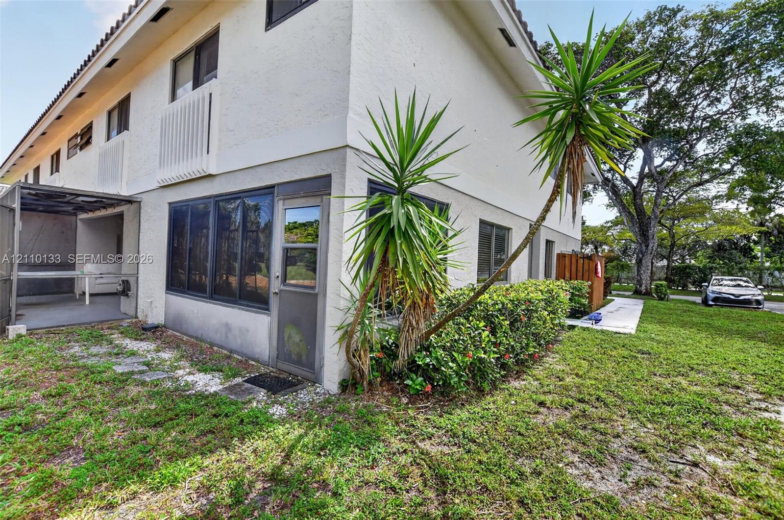Two-story exterior with stucco finish, enclosed patio, and mature landscaping